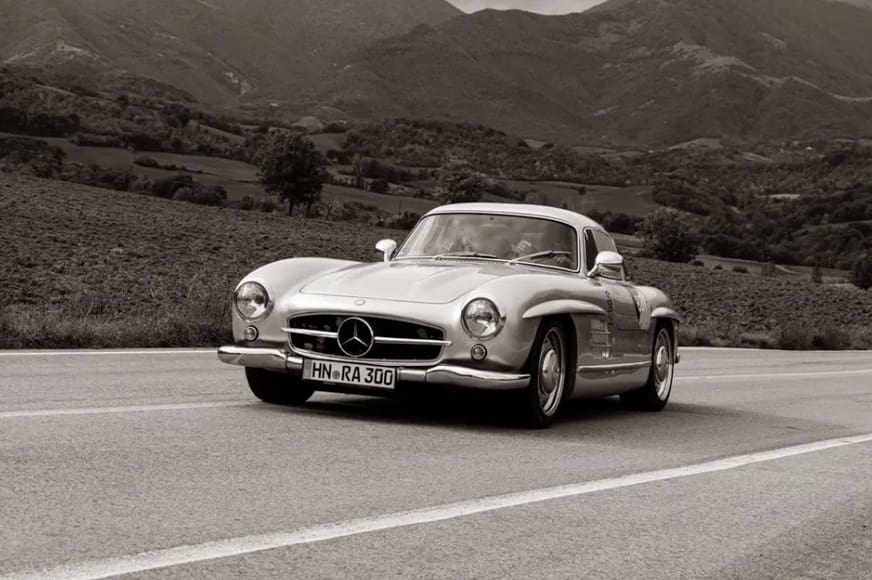 Classic Car Investments Silver Mercedes 300SL Gullwing driving through countryside