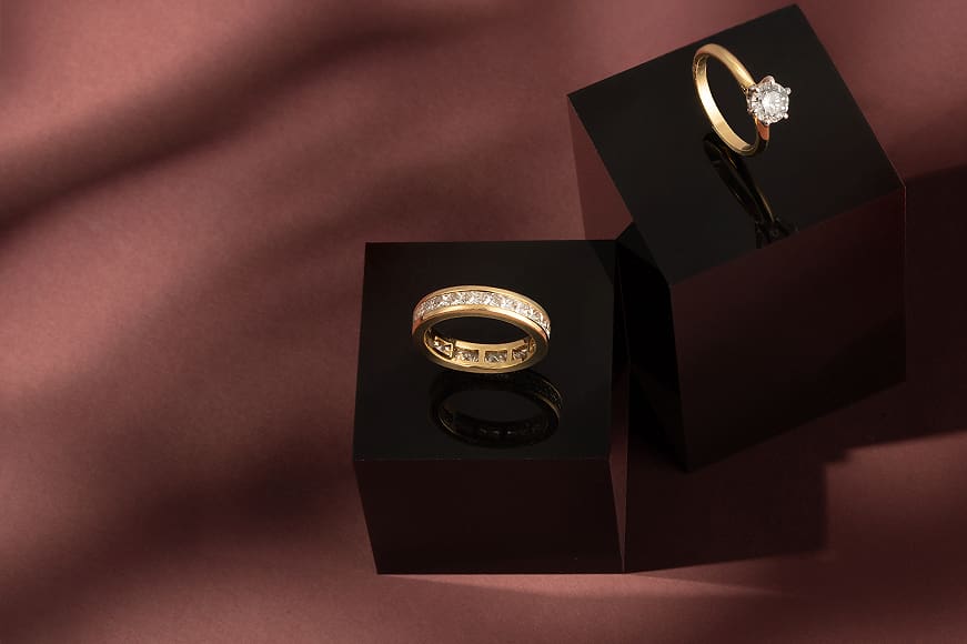 18K Yellow Gold Half Eternity Ring with Princess Cut Diamonds & Certificated Tiffany and Co. 18K Yellow Gold Solitaire Diamond Ring on a dusky pink background