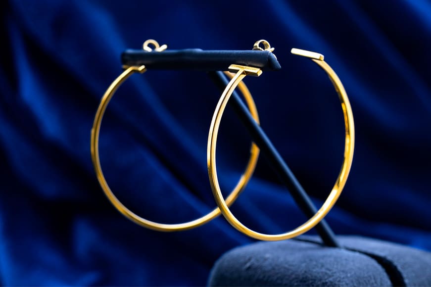 Tiffany & Co. T earrings in yellow gold on a blue background